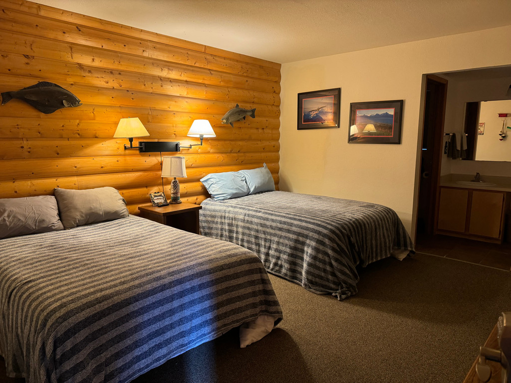 Standard room with two double beds and warm log wood headboard wall