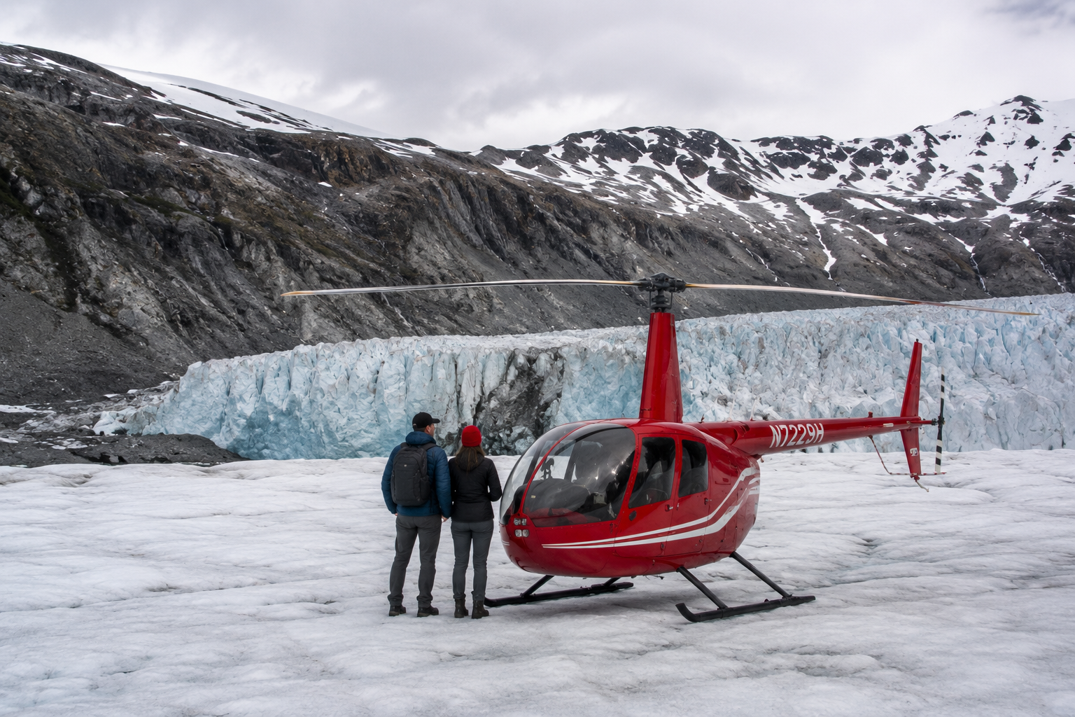 Couple standing beside a red helicopter on a glacier with snowy mountains behind